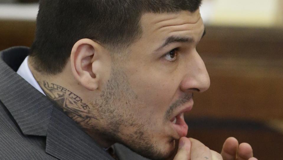 Sporting a new neck tattoo former New England Patriots NFL football player Aaron Hernandez sits at the defense table during his arraignment on a charge of trying to silence a witness in a double murder case against him by shooting the man in the face at Suffolk Superior Court, Thursday, May 21, 2015, in Boston. Hernandez was convicted last month in the 2013 murder of Odin Lloyd. (AP Photo/Stephan Savoia, Pool)